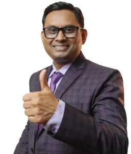 Ashish Mudra, India’s first Sales Transformation Coach, giving a confident thumbs-up gesture in a business suit.